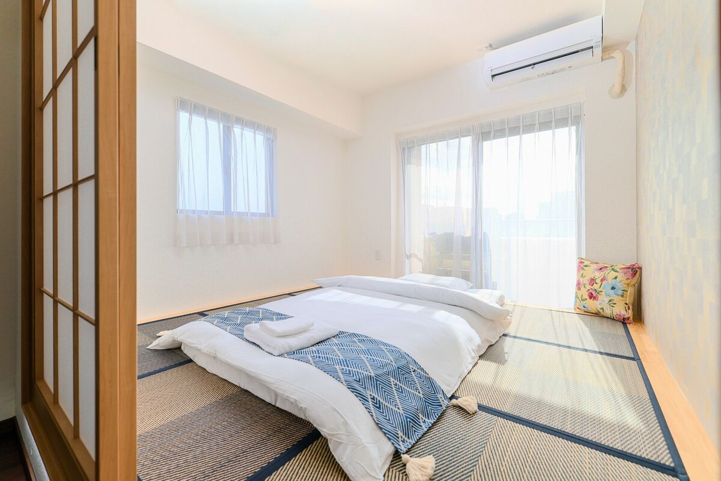 Japanese-style bedroom with a futon on tatami mats, sliding glass doors, and a shoji screen.