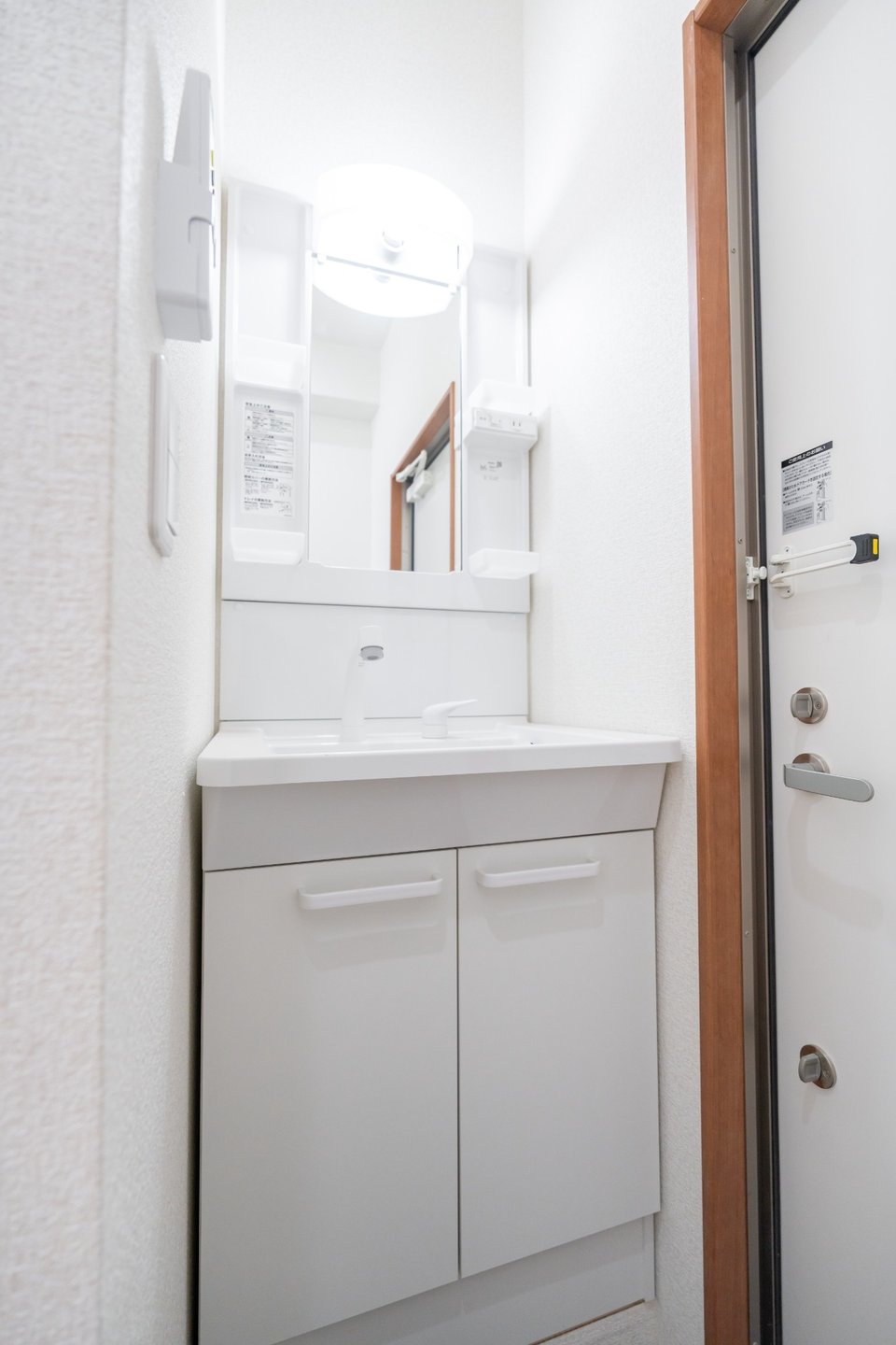 Compact white bathroom vanity with a sink, mirror, and cabinet next to a doorway.