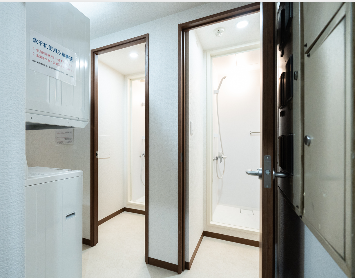 Washing machine and dryer next to two separate shower stalls in a bright bathroom area.
