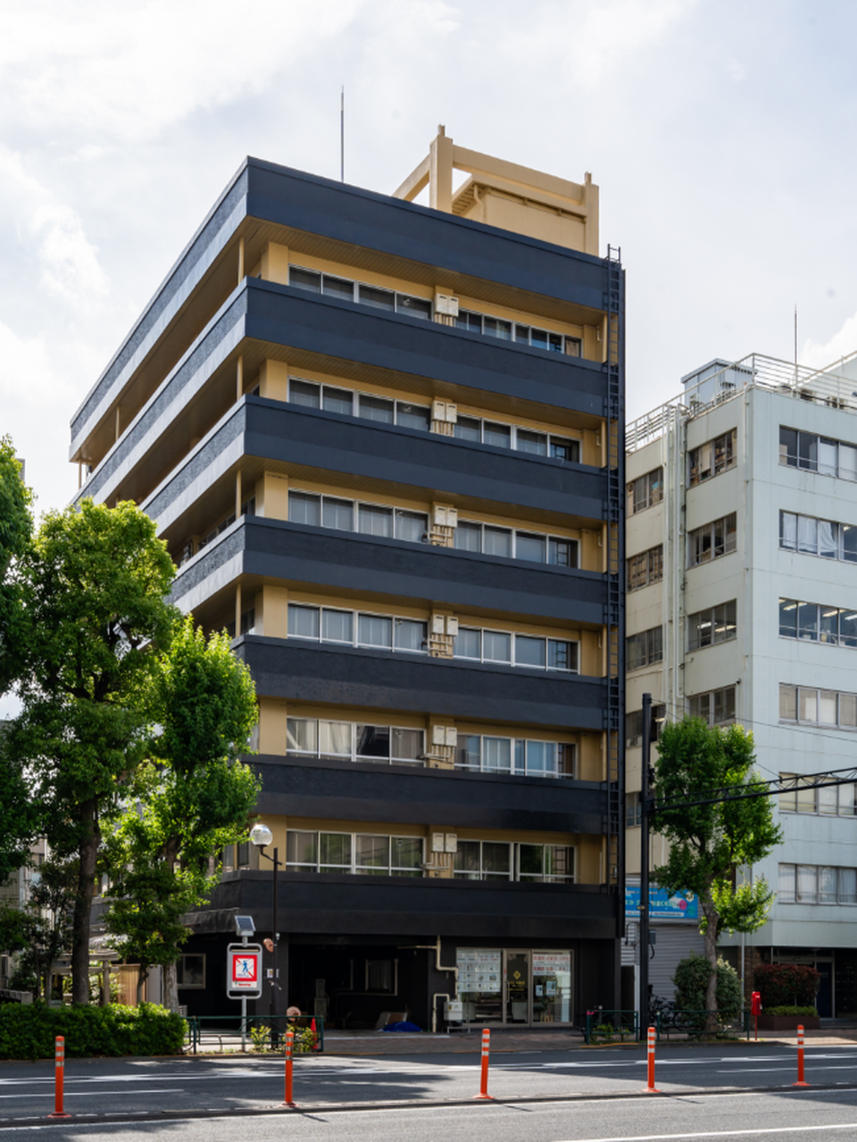 Multi-story black and beige apartment building on a city street in Tokyo.