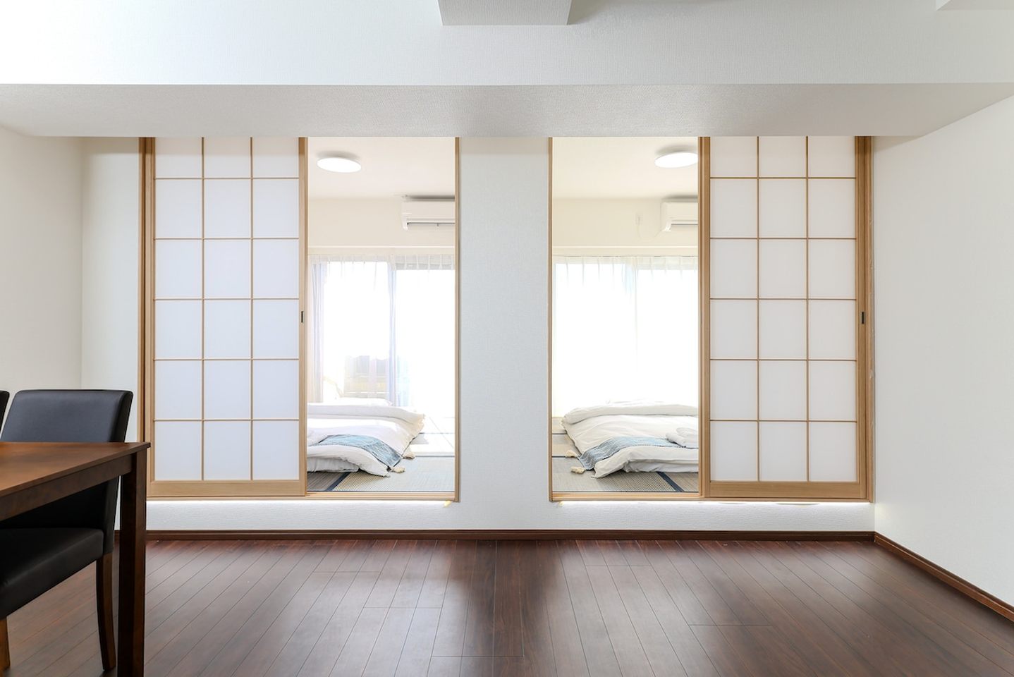 Japanese tatami bedroom with futons seen through sliding shoji doors from a wooden floor room.