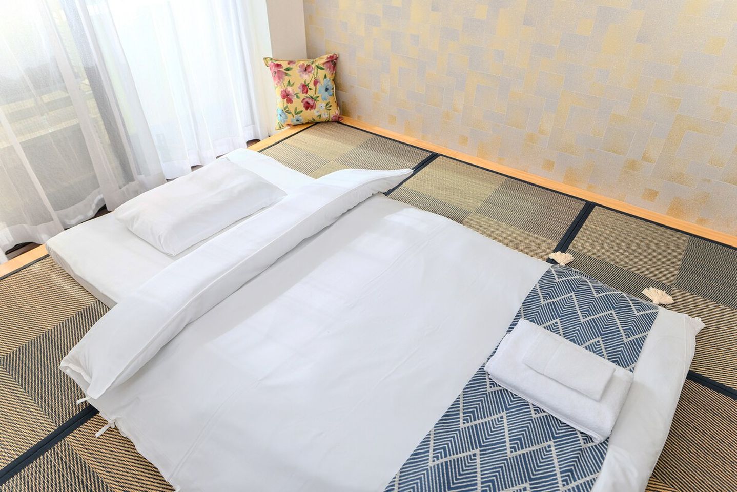 Traditional Japanese futon with white bedding laid on tatami mats.